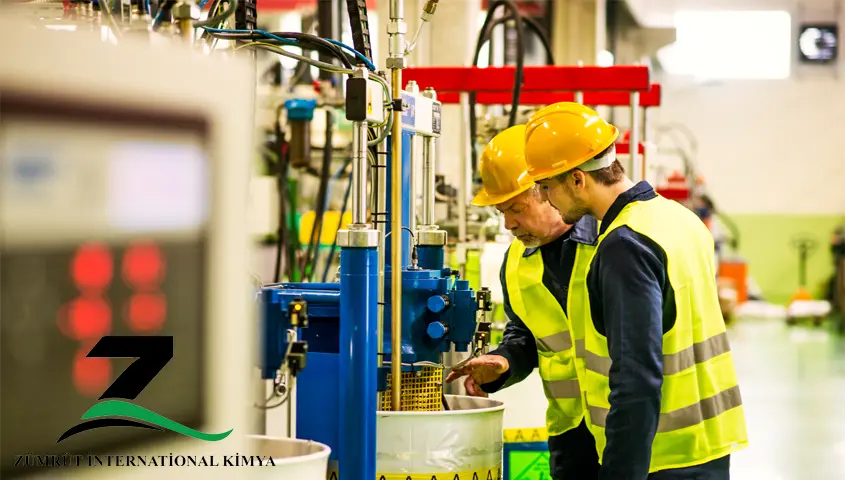 White caustic soda (NaOH) flakes in a chemical manufacturing facility, stored in containers with workers in protective equipment, highlighting industrial production and safe handling processes.